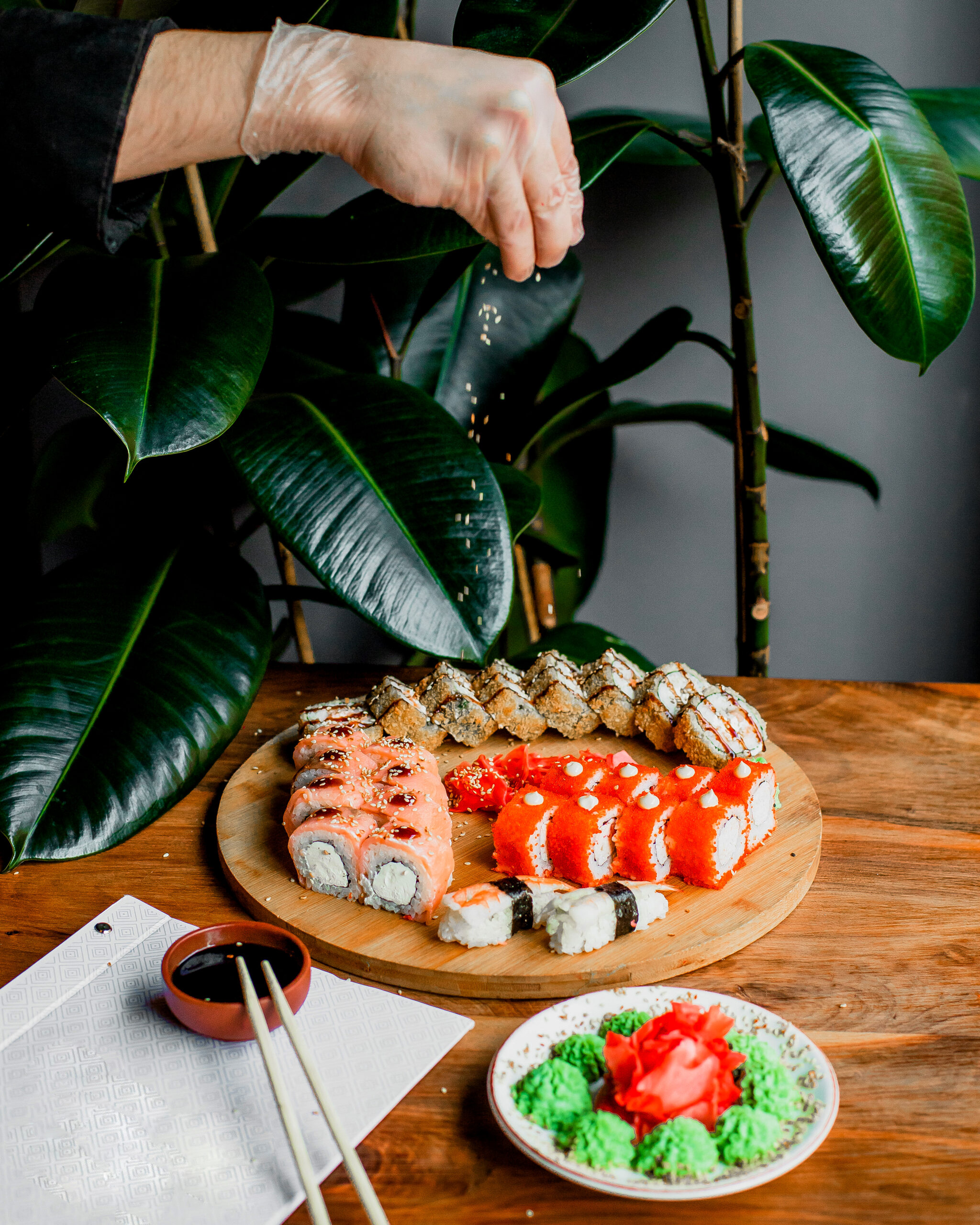 rolls-made-from-fish-wooden-round-surface-along-with-sticks-black-sauce-grey-surface